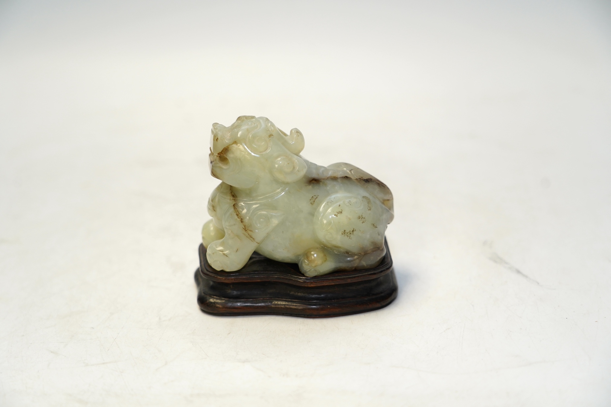 A Chinese carved jade ‘lion dog’ and stand, 8cm tall. Condition fair to good.